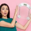 A woman holding up weighing scale