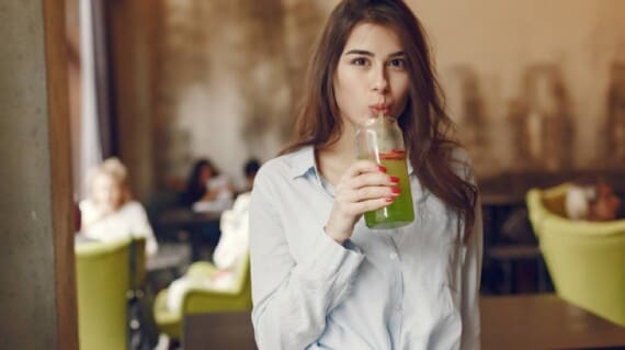 A woman drinking green juice.
