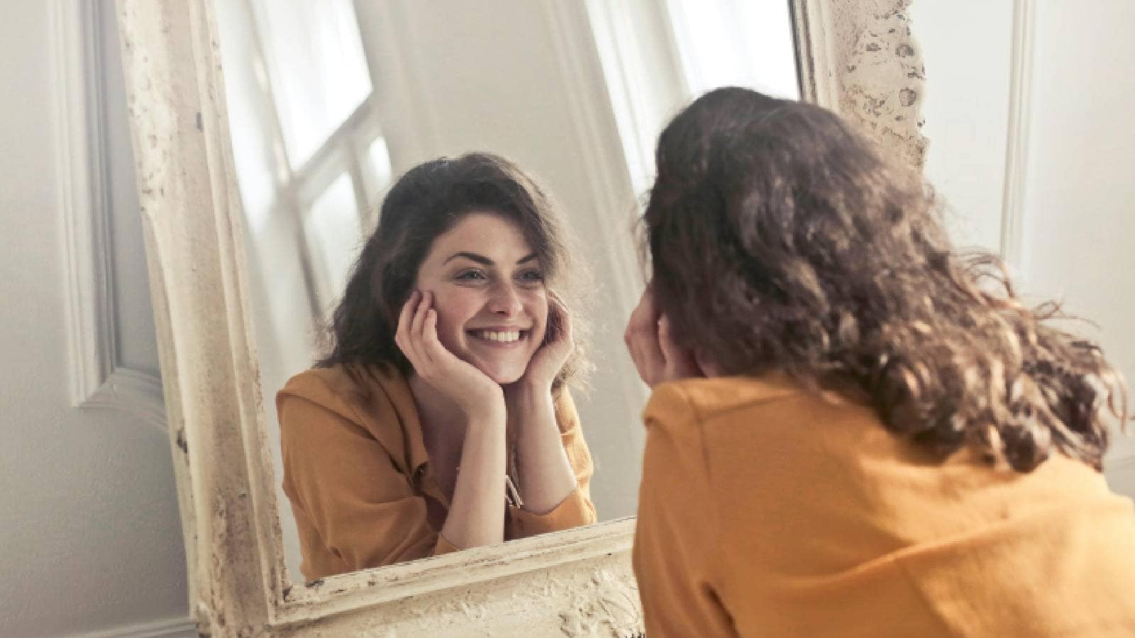 A woman smiling at herself in the mirror
