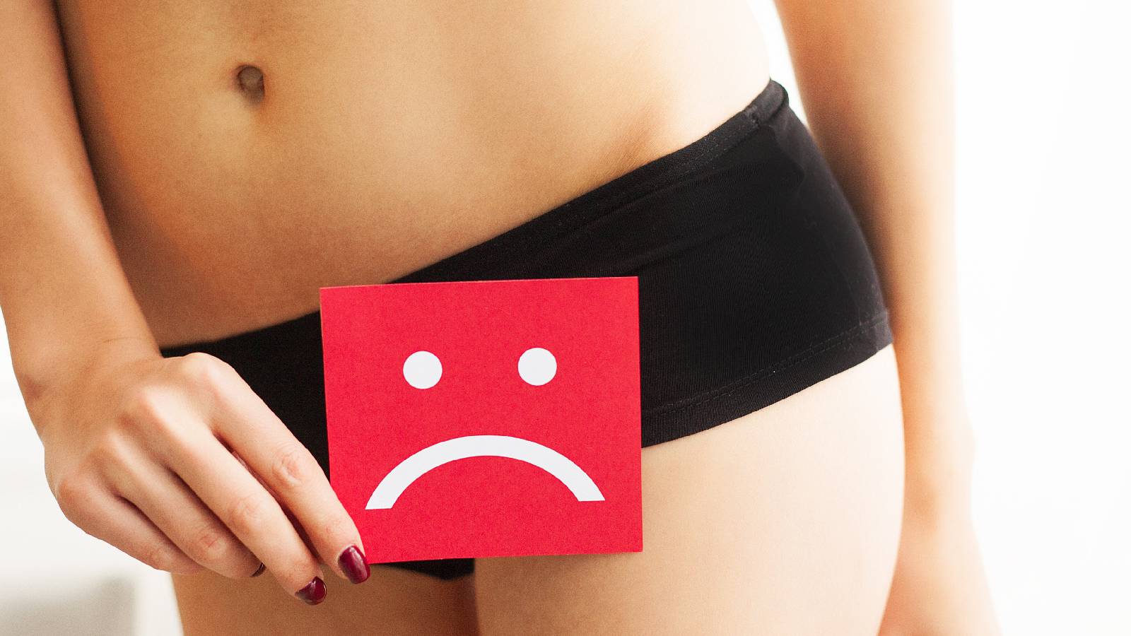Woman holds paper with sad smile above crotch